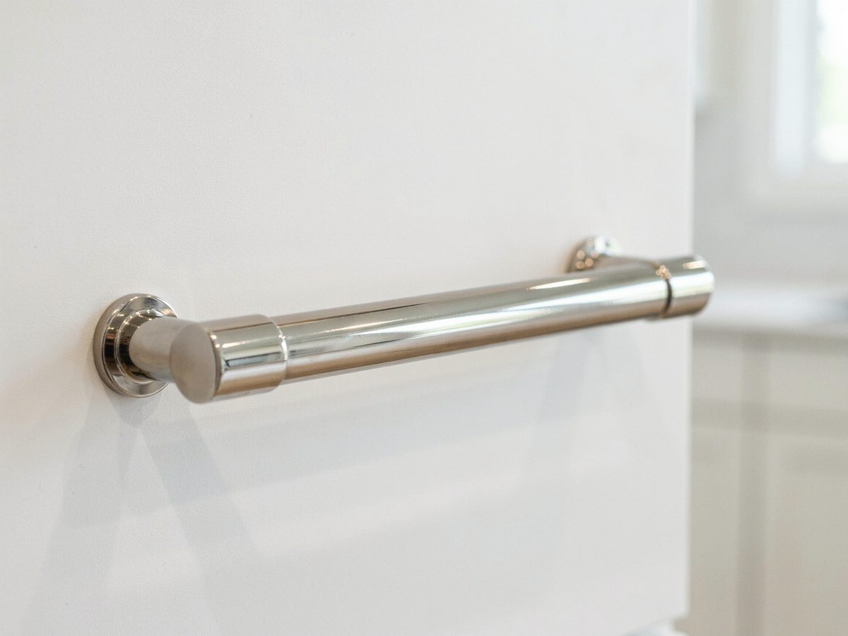 Polished nickel pull reflecting light against a bright white cabinet