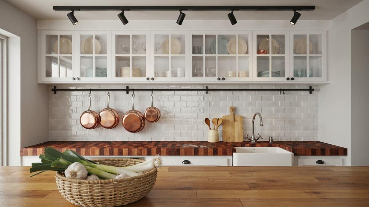 Glass front uppers, track lighting and copper pots hanging above a butcher block run