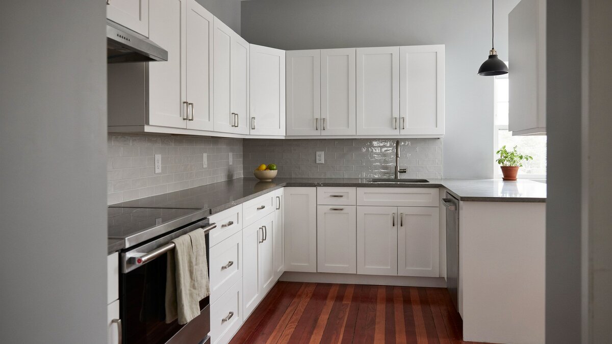 White thermofoil doors paired with gray quartz counters above deep cherry wood flooring