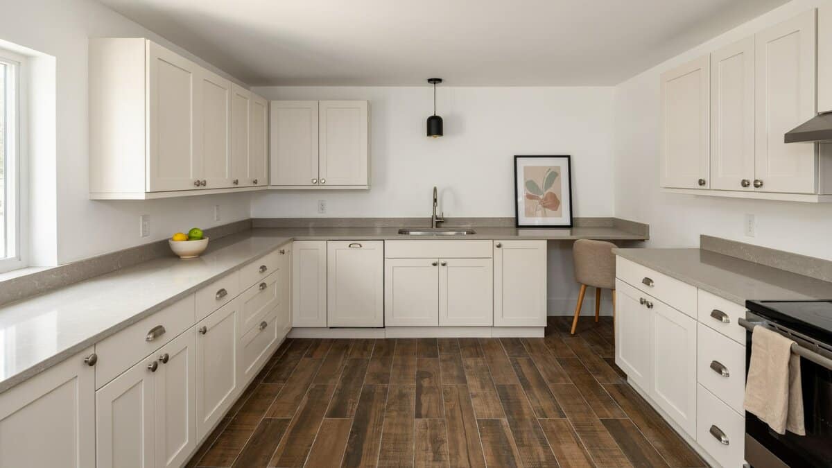 Warm white cabinetry with light gray counters, framed art and faux wood floor tiles