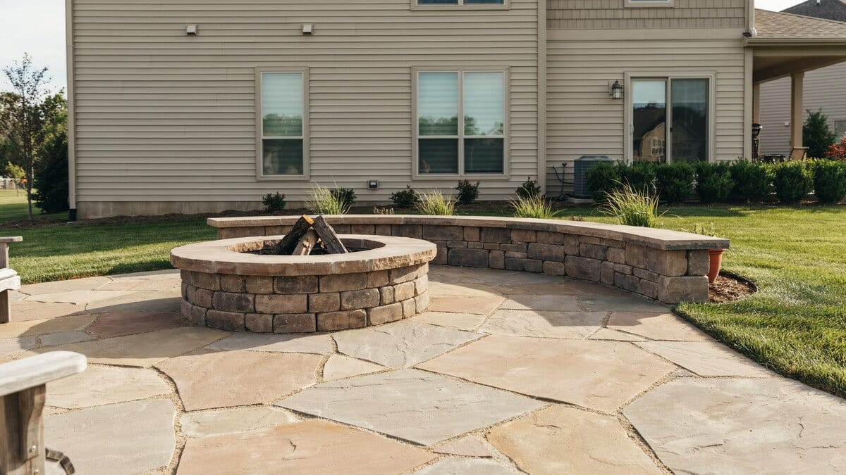 Round stone fire pit paired with a matching curved stone bench seating wall