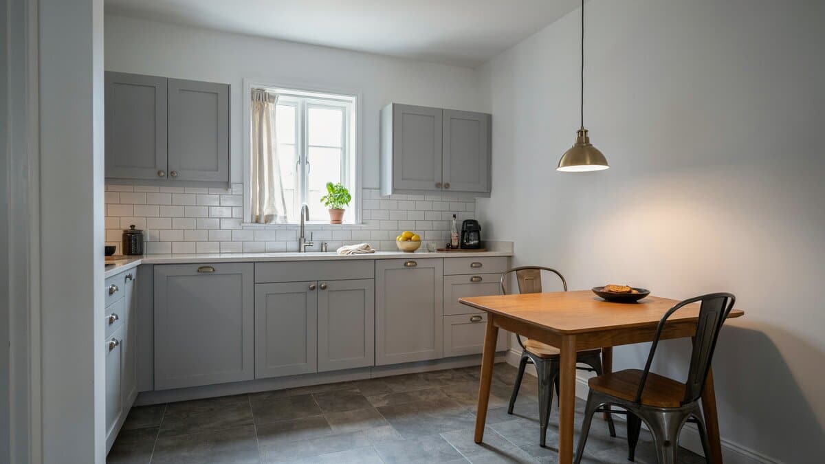 Dove gray flat panel cabinets with a wood table and metal chairs on slate flooring