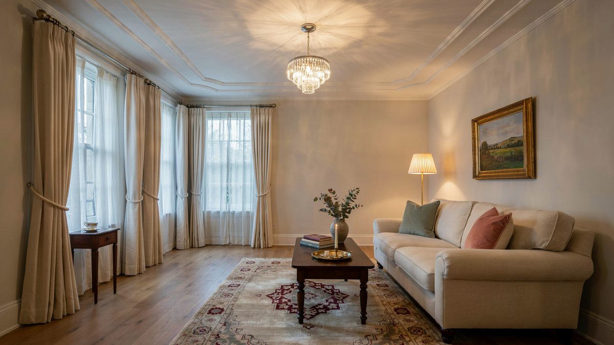 Tiered glass chandelier glowing warm above a cream sofa under a stepped tray ceiling
