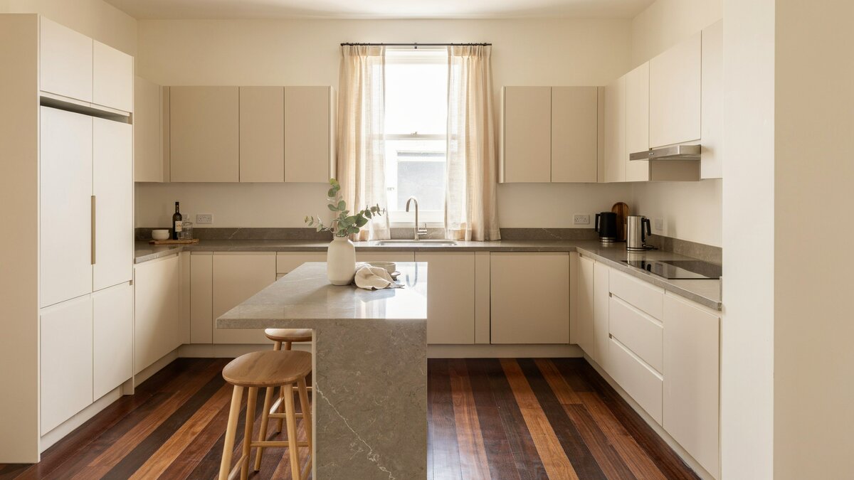 Ivory slab cabinets and gray corian counters set against dark wenge wood floors