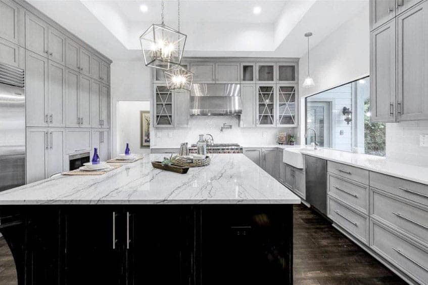 U shaped kitchen with gray cabinets stainless steel door handles marble countertops and dark island