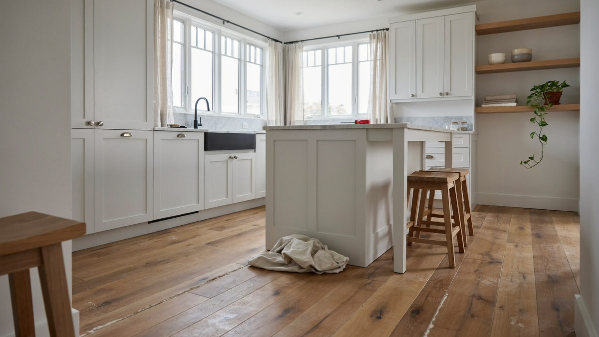 Kitchen island in a white room above raw unfinished oak boards