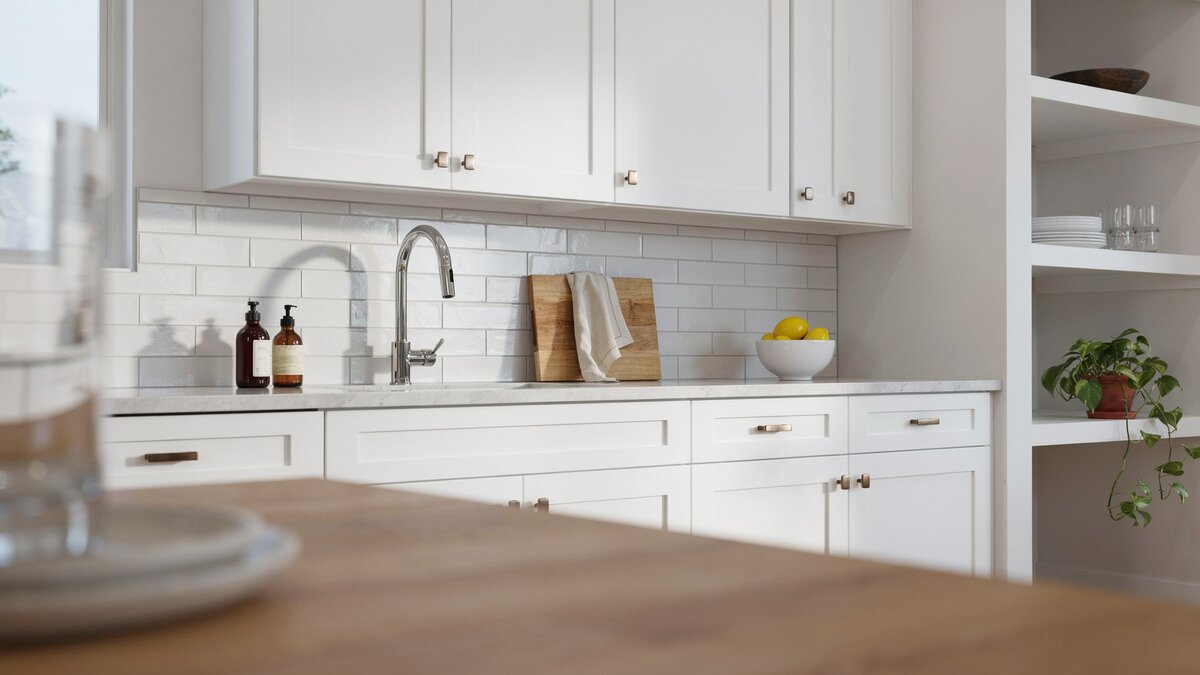 White shaker kitchen with stainless faucet and marble-look quartz countertops