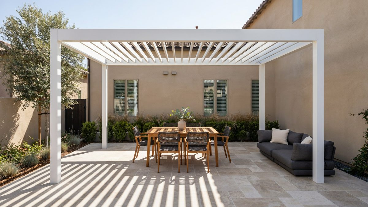 White louvered metal pergola casting striped shade on a stone patio