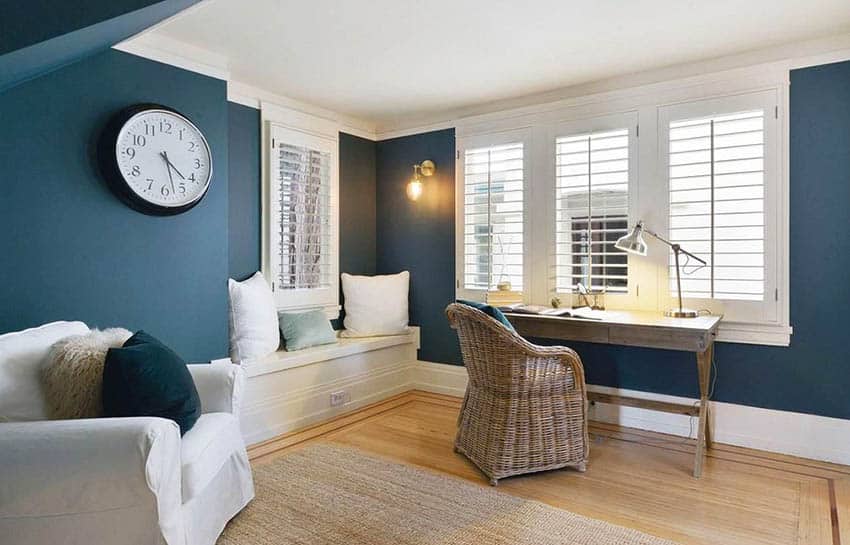 Home office with blue walls, rattan chair and round wall clock