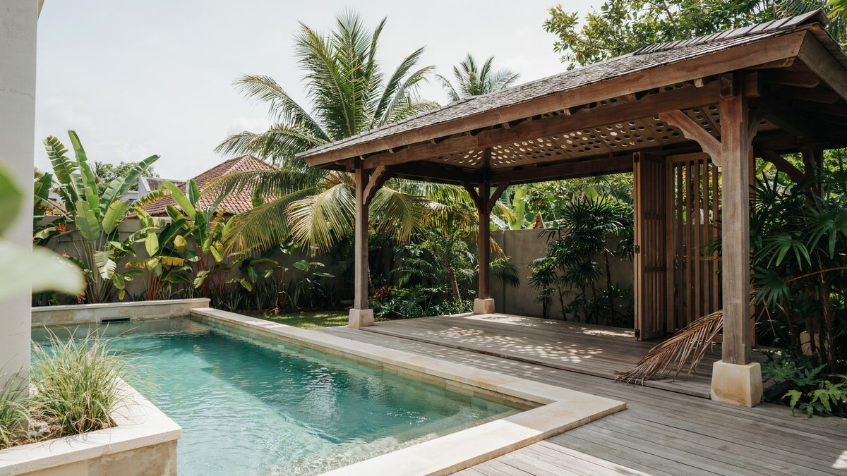 Balinese style poolside pergola with a solid rain roof and timber posts