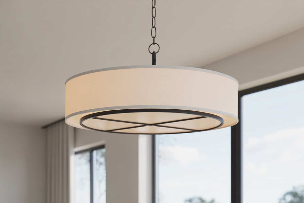 White fabric drum pendant on a black chain near tall bright windows