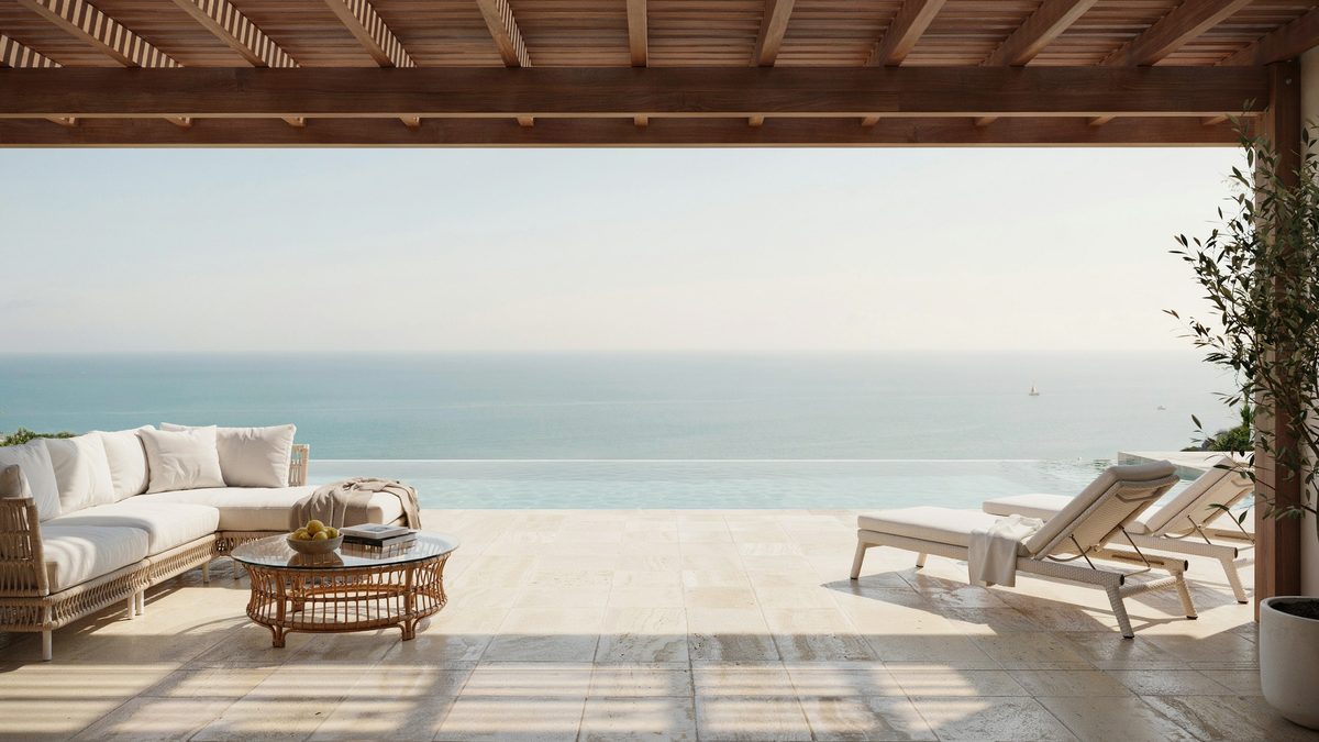Covered oceanfront patio with cream woven rattan furniture beside an infinity pool