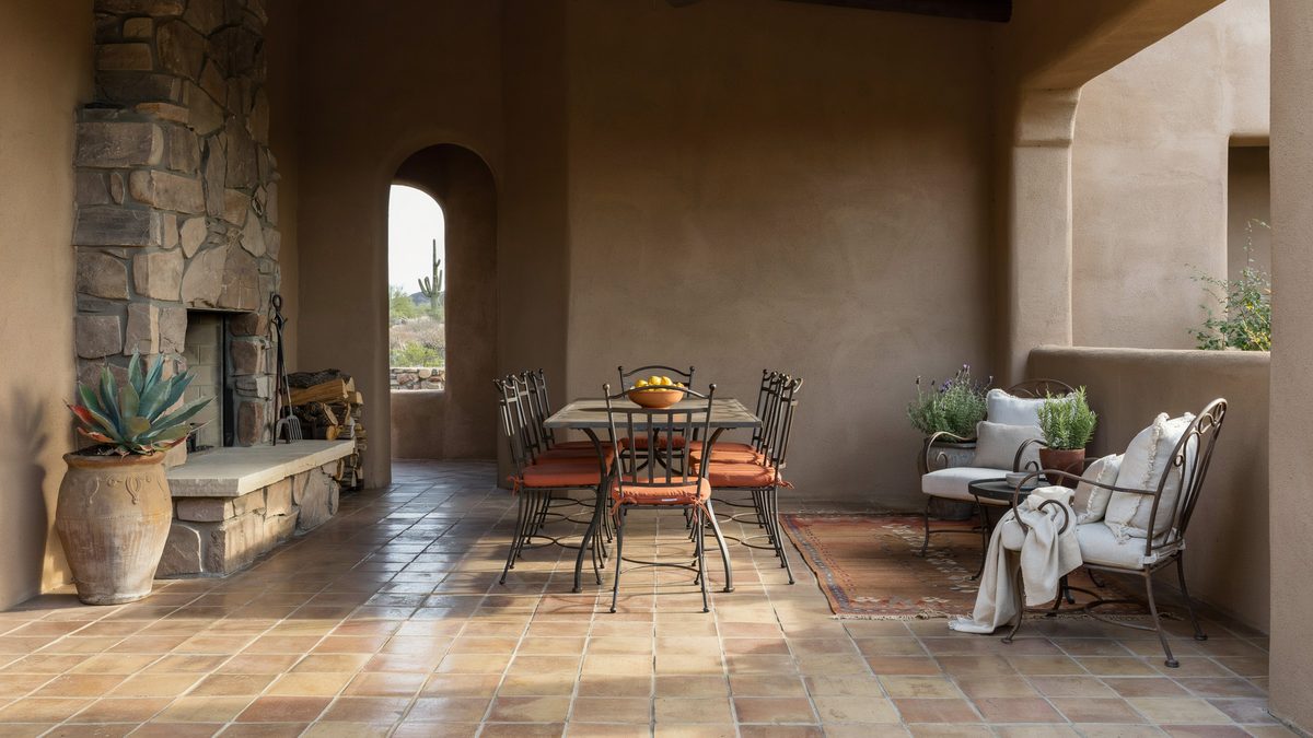 Stone masonry fireplace patio with bent iron seats and white cushions