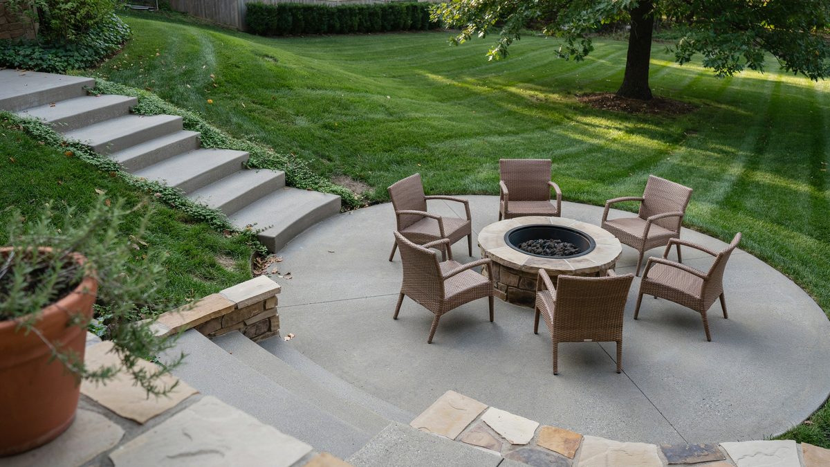 Round sunken patio with six wengue rattan chairs around a built in fire pit