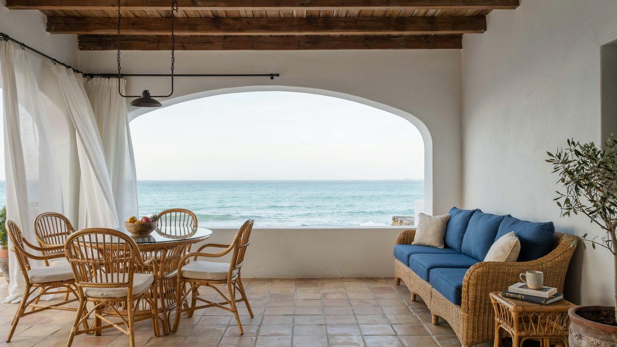 Covered coastal patio with rattan dining set and blue pillowed couch