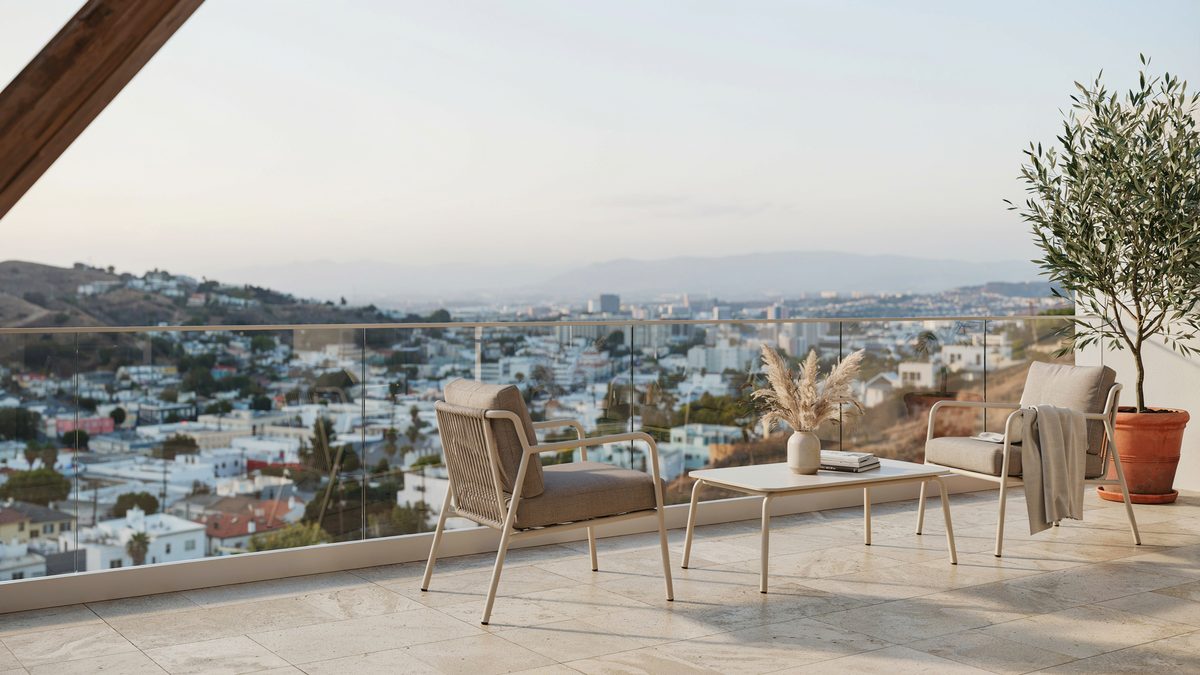 Hillside balcony patio with glass railings and taupe cushioned metal furniture