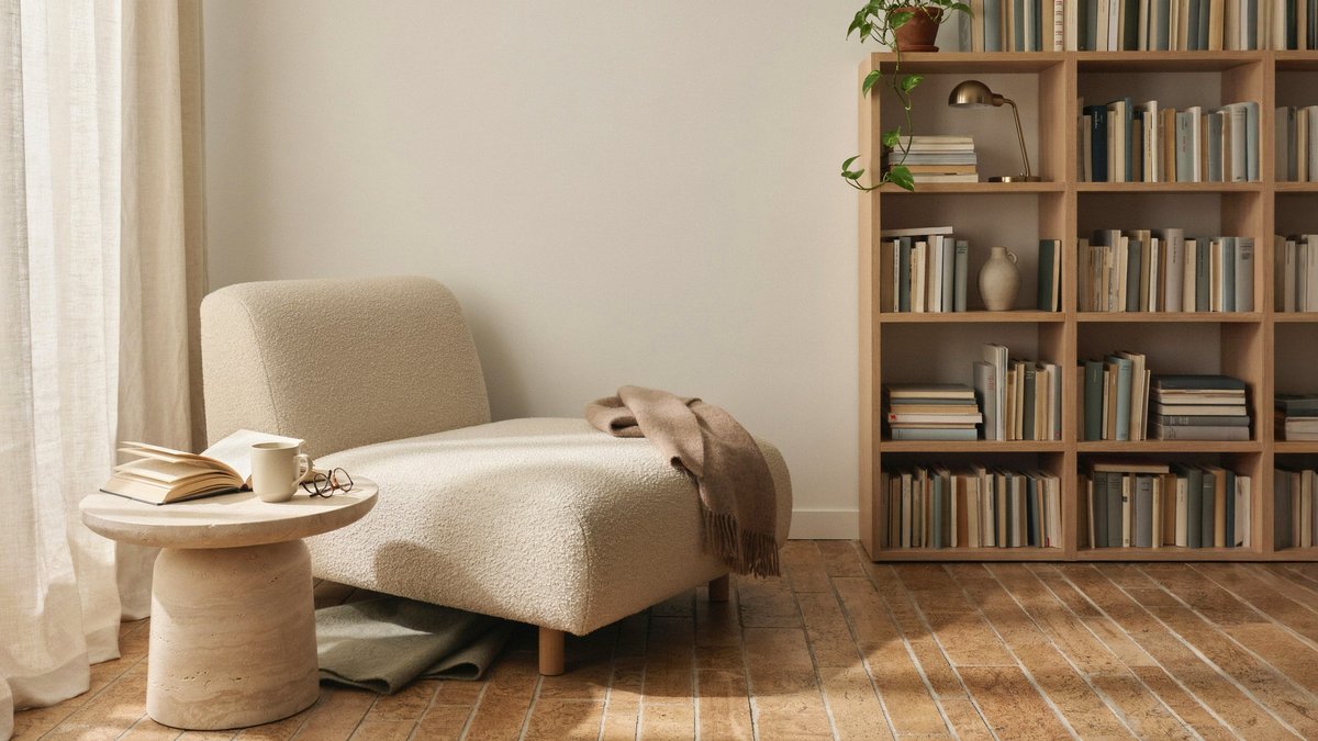 Narrow slat cork boards by a boucle chaise and oak bookshelf