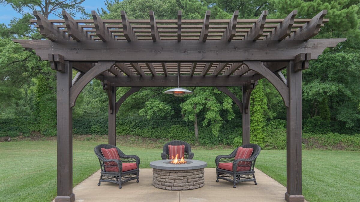 Dark stained pergola with decorative rafter tails over round stone fire pit with wicker chairs and red cushions