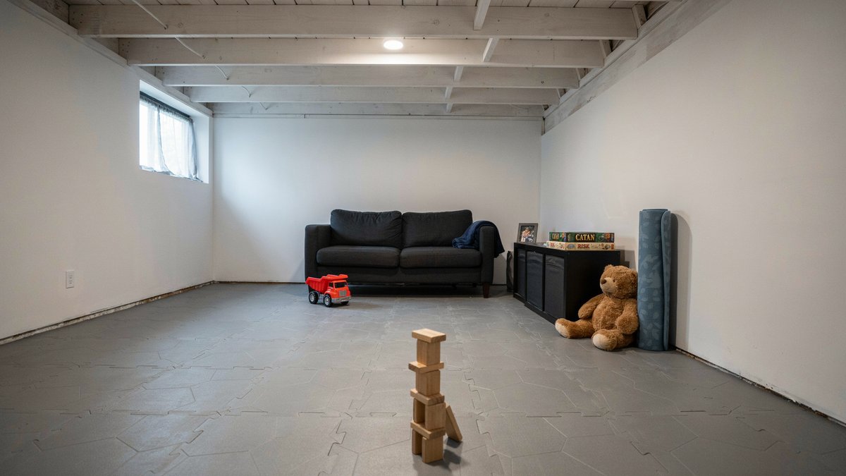 Gray interlocking rubber tiles across an open playroom with black couch