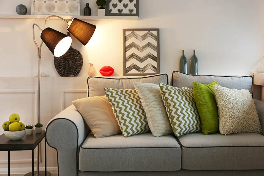 Gray couch with green accent pillows and floor lamp