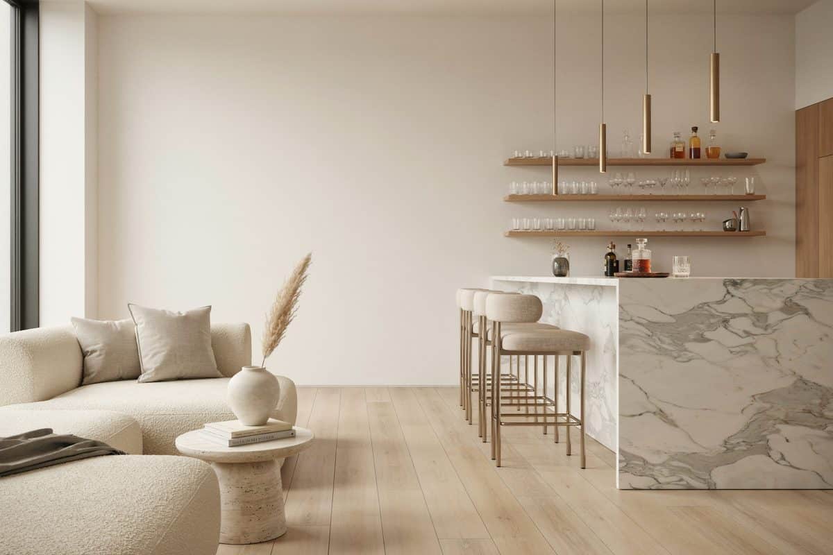 White marble waterfall bar counter with open brass shelving and cream stools