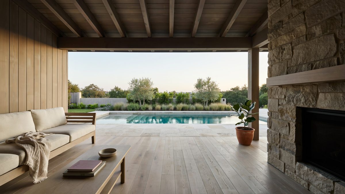 Semi open patio with pale oak table and fireplace facing the pool