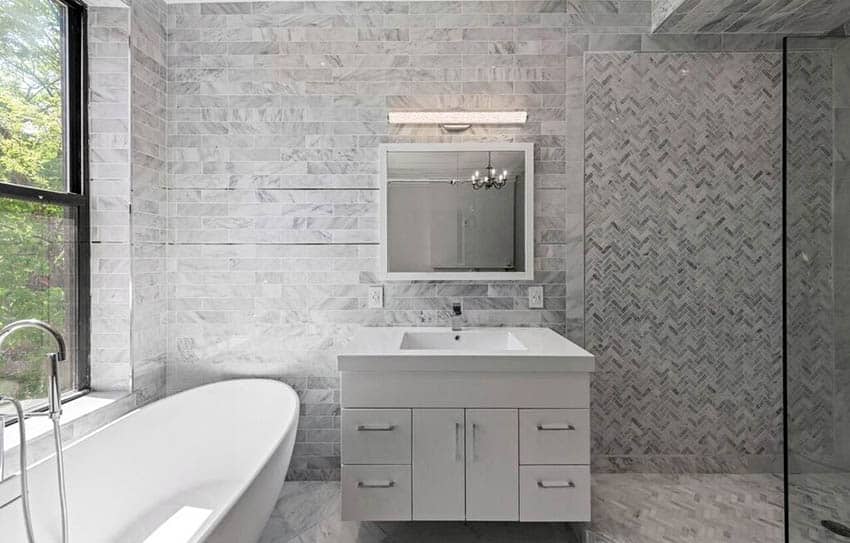 Modern bathroom with single sink vanity marble tile walls and freestanding tub