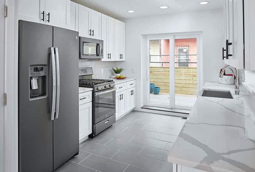 Modern galley kitchen with white quartz countertops, white cabinets and sliding glass door