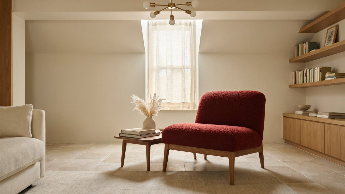Pale limestone tile framing a crimson accent chair under a tall window