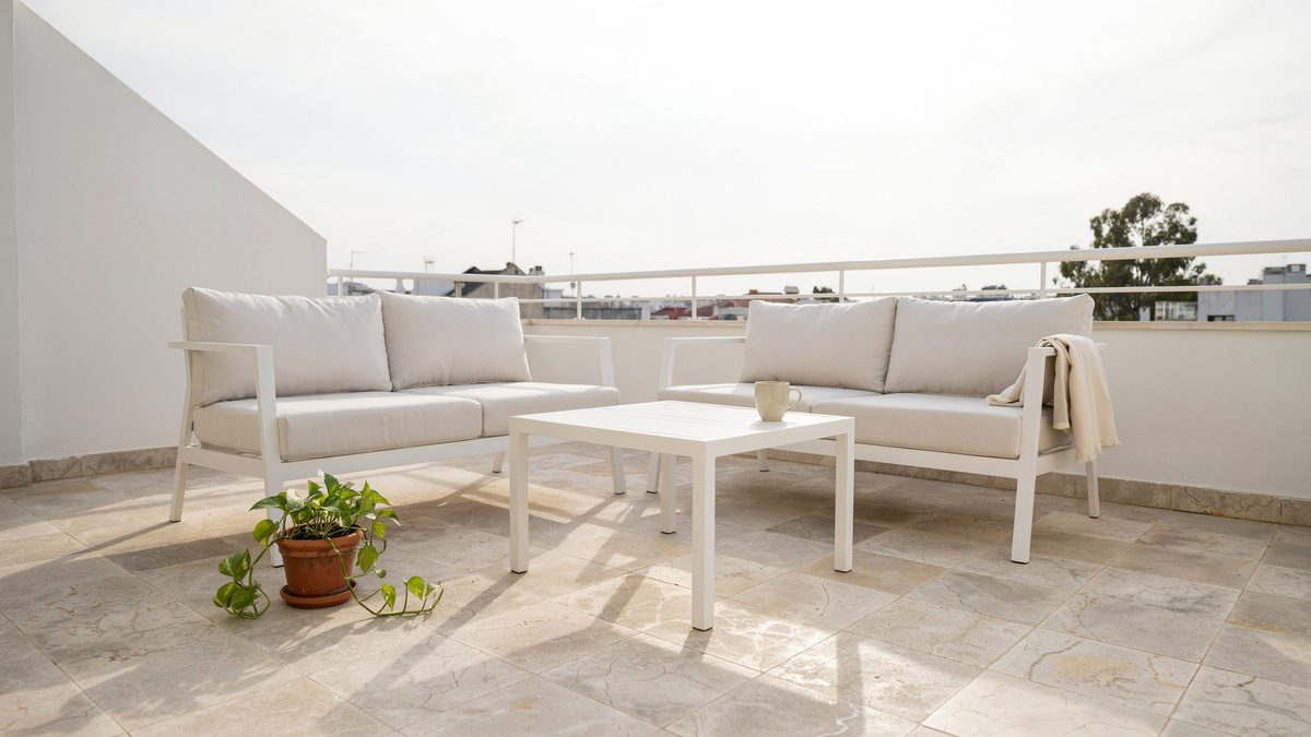 Open balcony patio with cream granite floor and two white lounge sofas