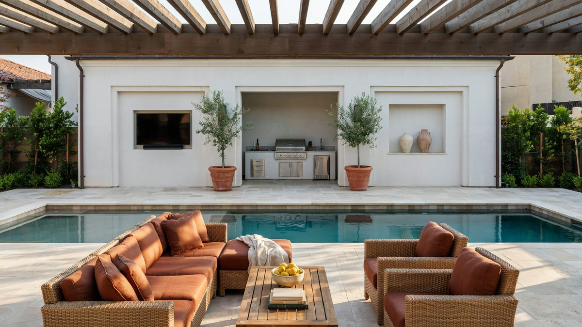 Poolside patio with covered living area, wall niches and outdoor kitchen