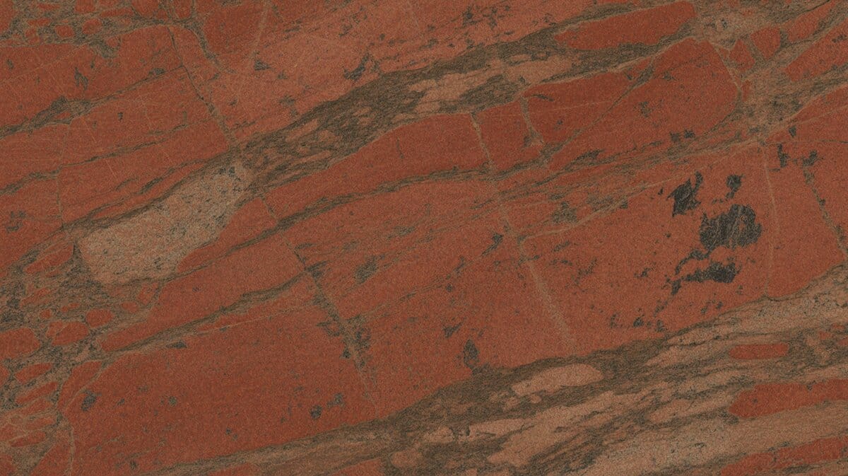Red Bordeaux granite slab with rich terracotta red base, dark brown diagonal veining and scattered black mineral patches