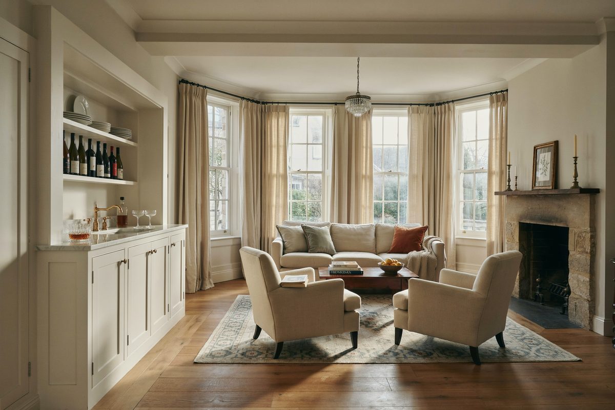 Bright traditional living room with white cabinet wet bar and stone fireplace