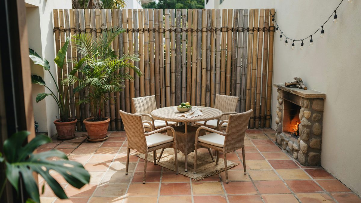 Small tropical patio with bamboo fence, palms and a corner fireplace