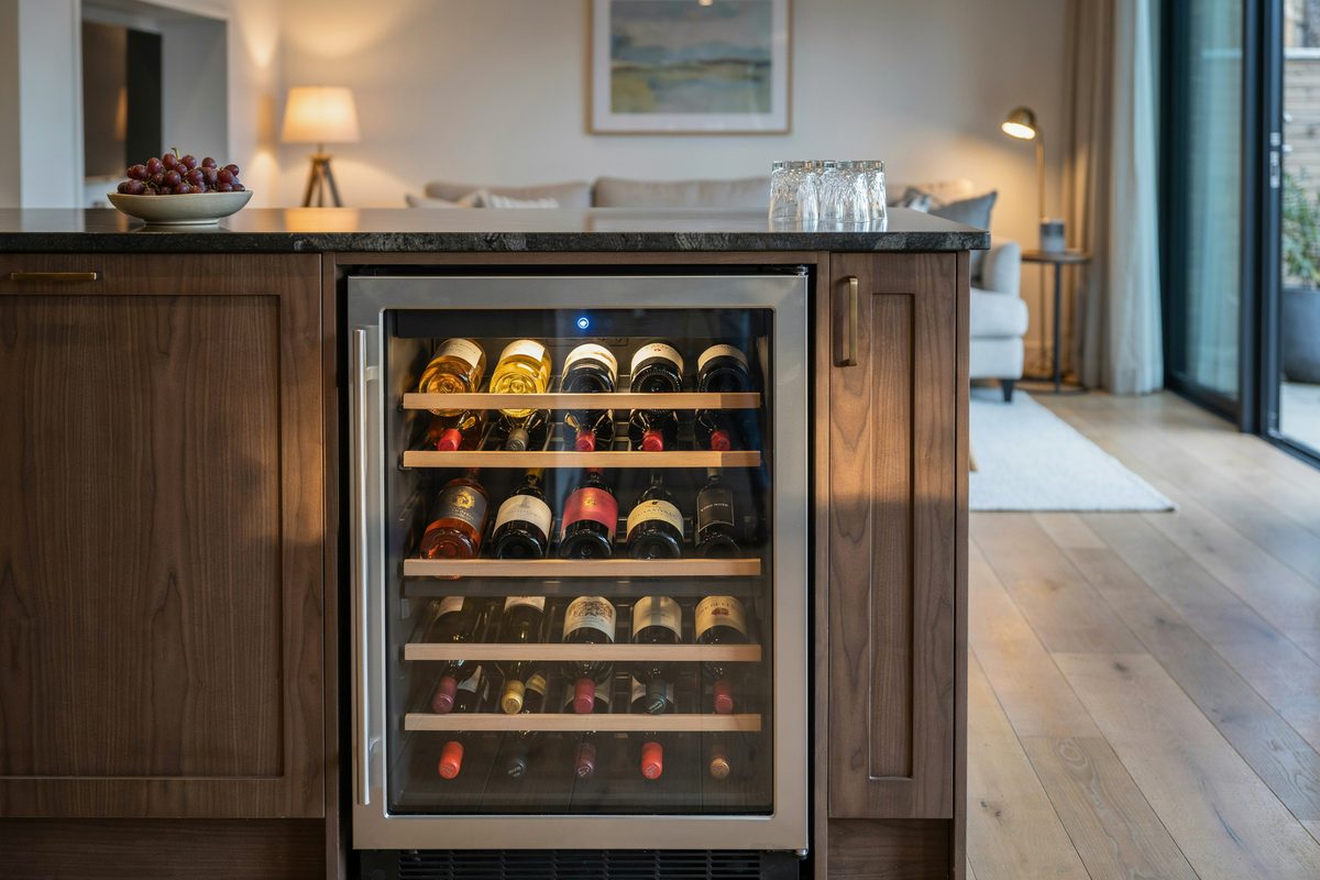Glass front wine refrigerator built into a dark wood bar island