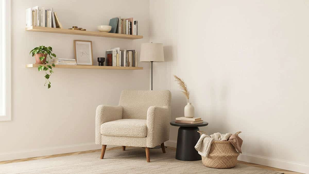 Wingback reading chair in a living room corner with wall shelf and blanket basket