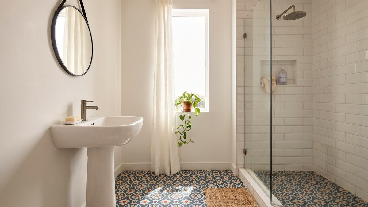 Patterned blue and orange Spanish floor tile with white subway tile shower