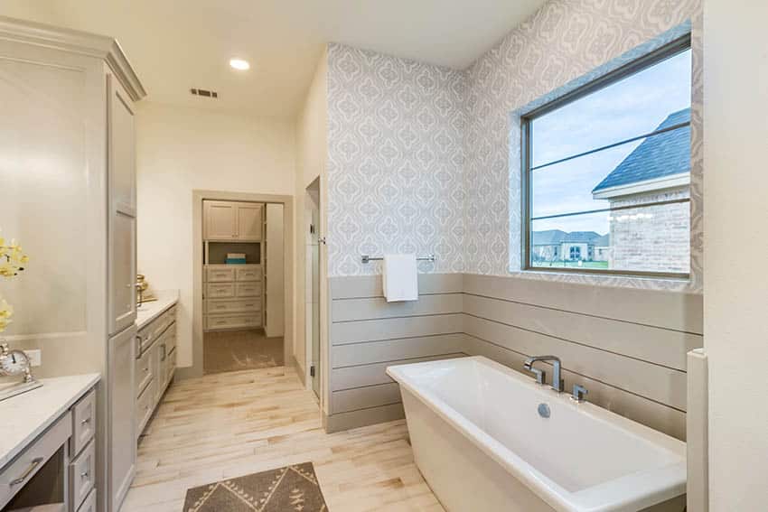 Bathroom with contrasting beige boards and pattern wallpaper wall surrounding tub