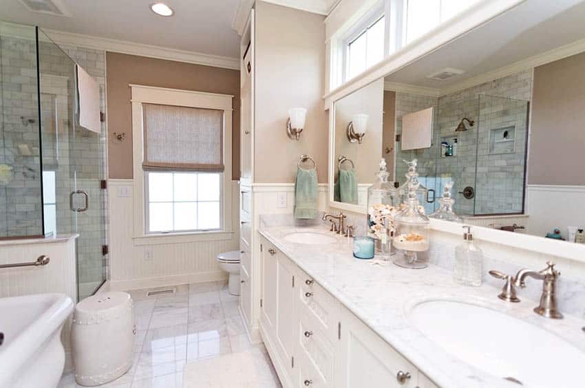 Bathroom with medium height wainscoting, brown paint and dual vanity 