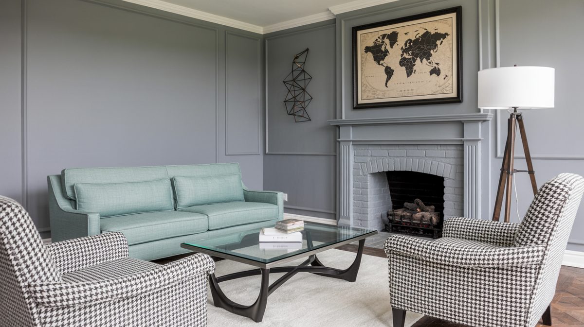 Gray living room with painted brick fireplace, aqua green sofa, and houndstooth accent chairs