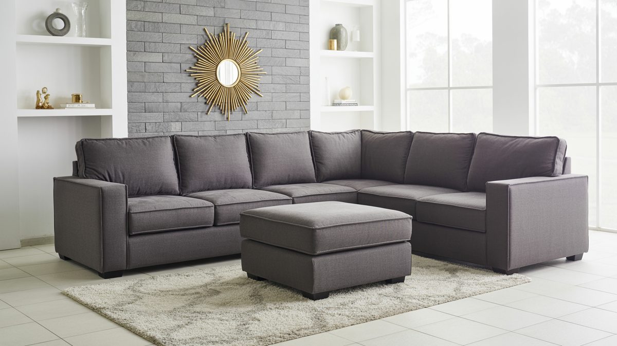 Gray sectional sofa with matching ottoman in front of a stone tile accent wall and starburst mirror