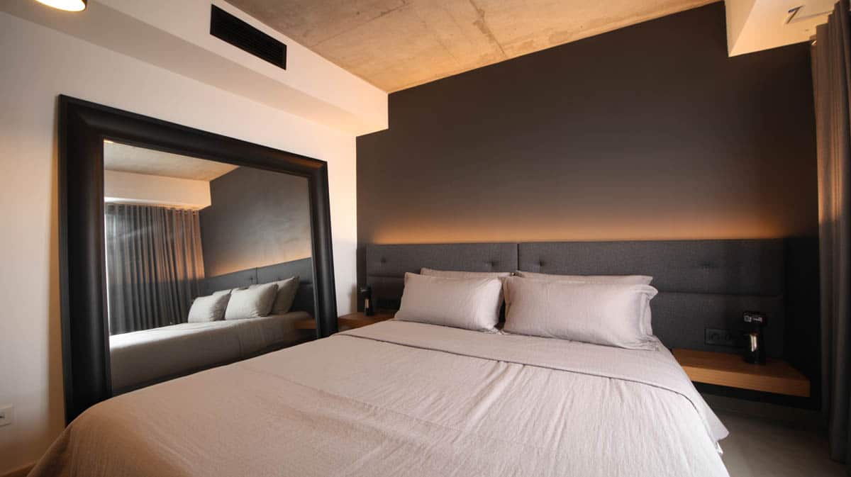 Loft bedroom with warm charcoal gray accent wall and large black-framed mirror