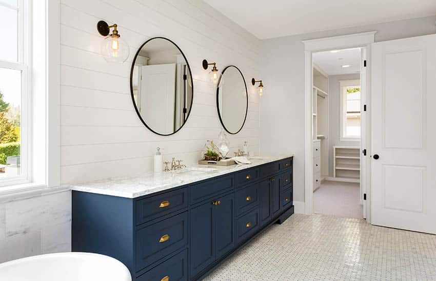 Modern farmhouse bathroom with white shiplap walls, dark blue vanity and gold hardware finishes