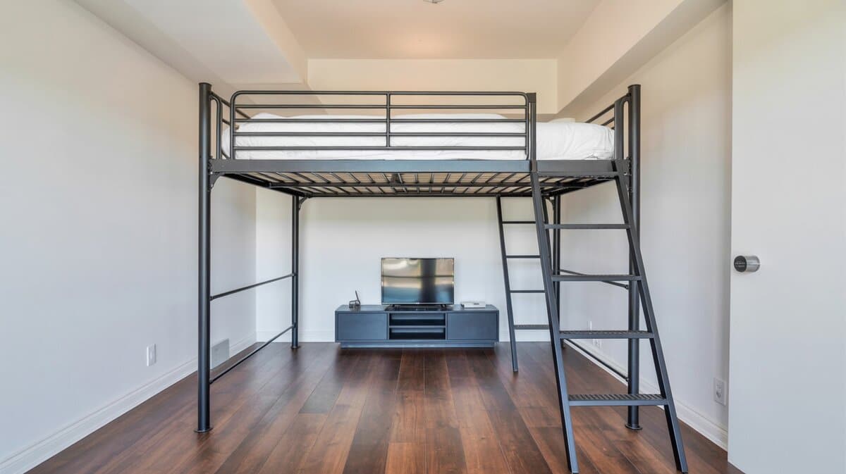Contemporary black metal loft bed with TV console and study area below in compact studio apartment