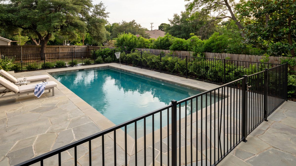Black aluminum tube fence enclosing a backyard in-ground pool and deck
