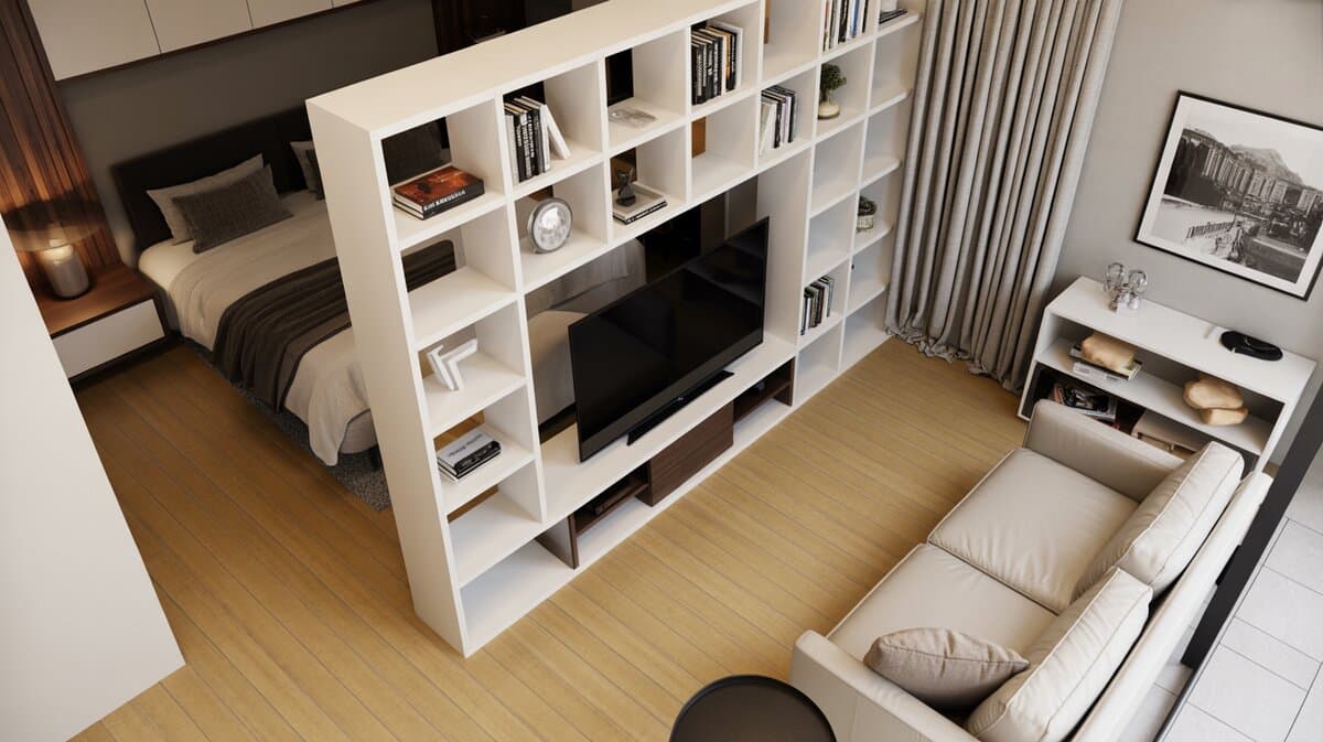 Contemporary studio apartment viewed from above with full-height white open bookcase room divider and TV mounted between bedroom and living areas