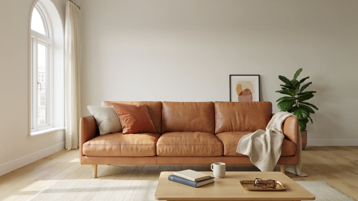 Tan leather sofa with a knit throw beneath a tall arched window