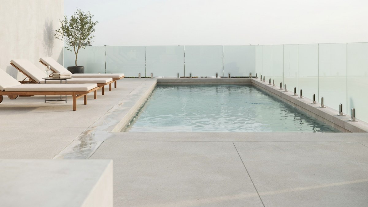 Frosted glass panel fencing giving privacy around a contemporary concrete pool deck