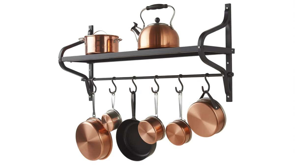 Black wrought iron rectangular wall-mounted pot rack with copper pots and tea kettles hanging from S-hooks