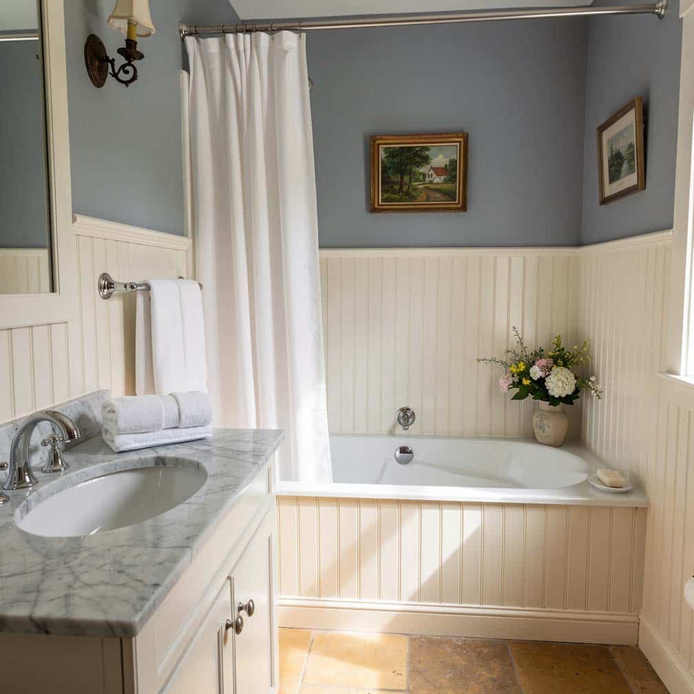 Narrow plank paneling with contrasting blue-gray upper walls and a marble sink countertop
